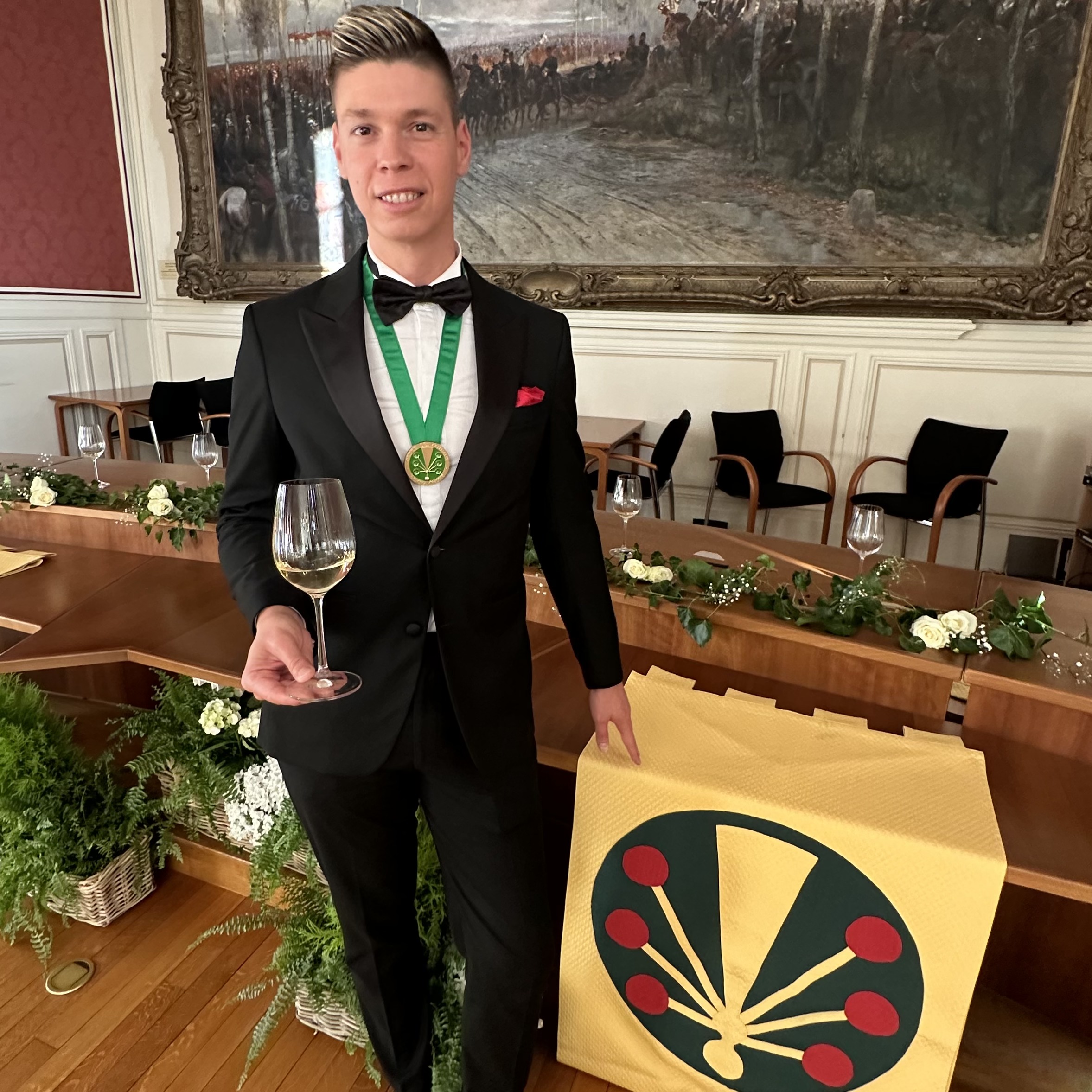 Mate Hajdu in black tie with the Chevalier medal before the OCC flag
